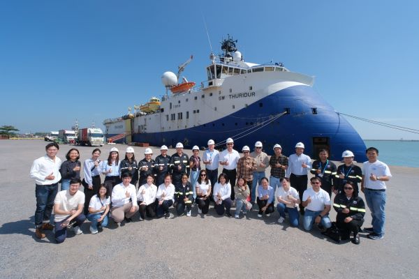 A group of people standing in front of a vessel
